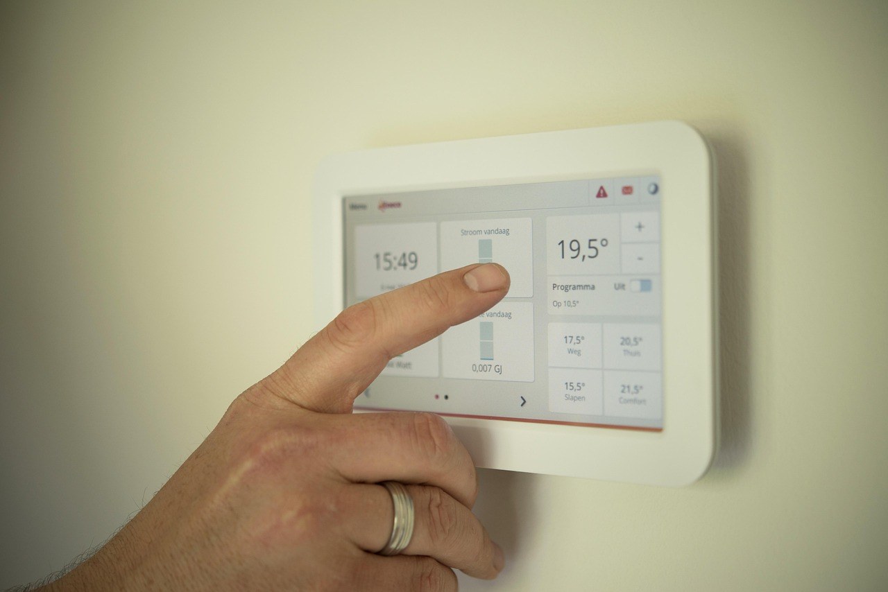 Doigt réglant un thermostat connecté mural