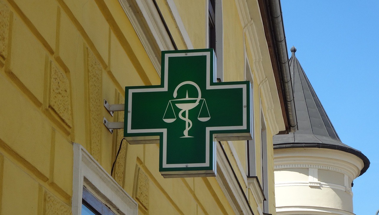 Croix verte de pharmacie sur une façade de village