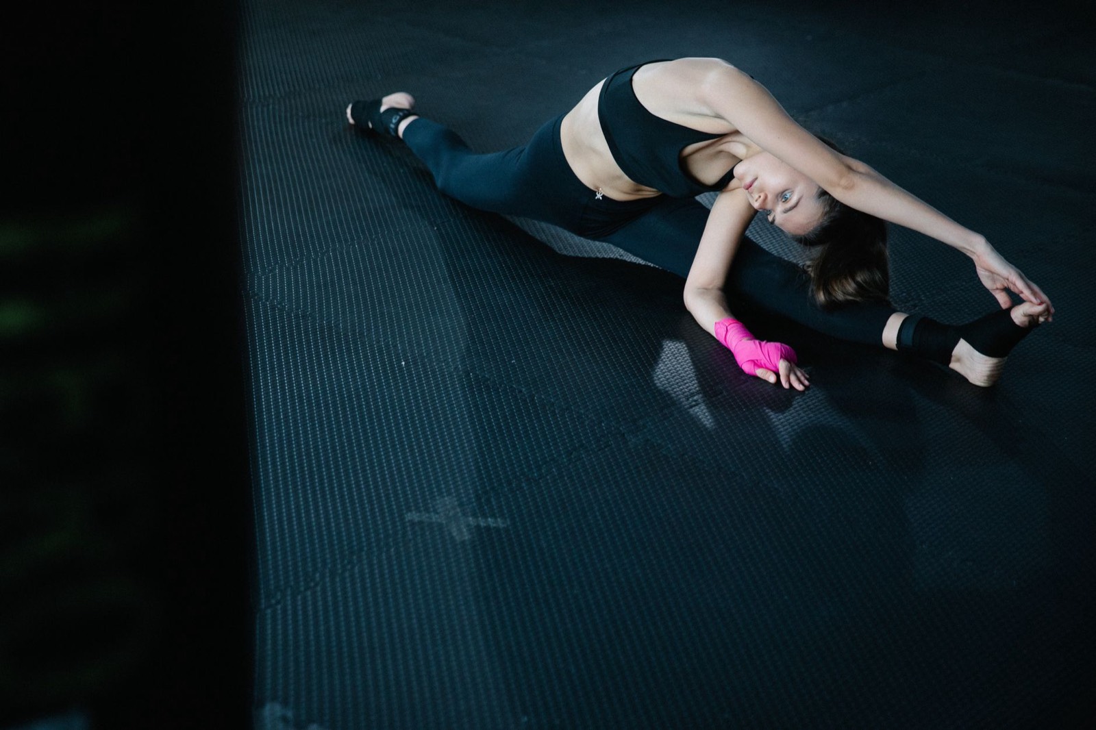 Femme qui s'étire sur un tapis de sport dans une salle