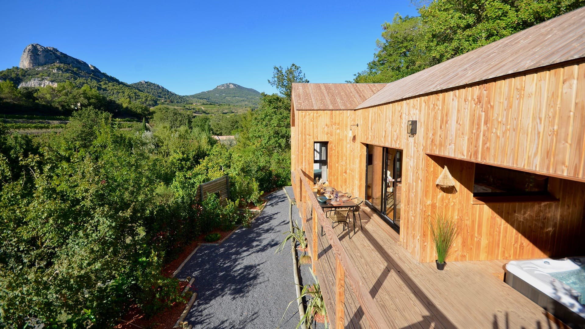 Terrasse en bois du lodge avec spa privatif et vue sur les Dentelles de Montmirail
